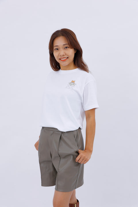 Front view of a smiling woman wearing the white "Shiba Inu" T-shirt and gray shorts.