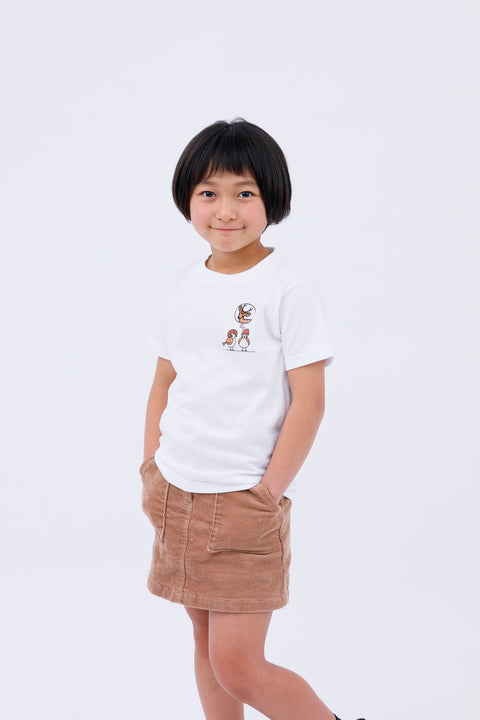 Front view of a smiling child wearing the white "Sparrow in Love" T-shirt and a brown corduroy skirt, standing casually.