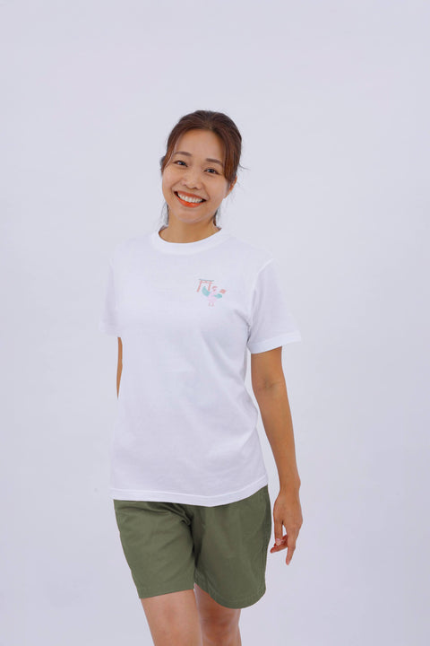 Front view of a smiling woman wearing the white "Dove" T-shirt and olive green shorts.