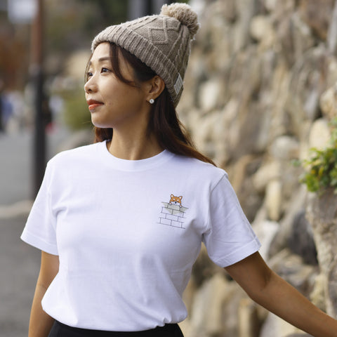 Model wearing a white tee with a small Shiba Inu pocket-style graphic.