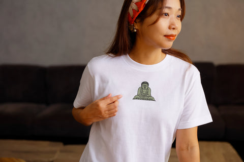 Model wearing a white T-shirt with the Kamakura Daibutsu graphic, pointing to the chest print.