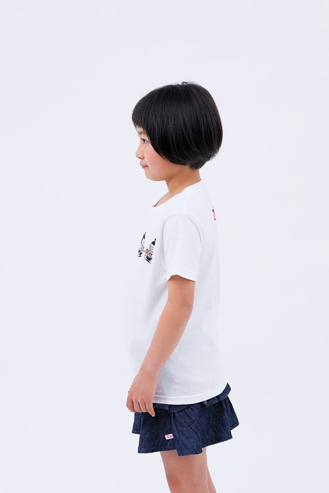 Side view of the child wearing the "Sumo Wrestler & Ayatori" T-shirt and skirt, smiling softly.