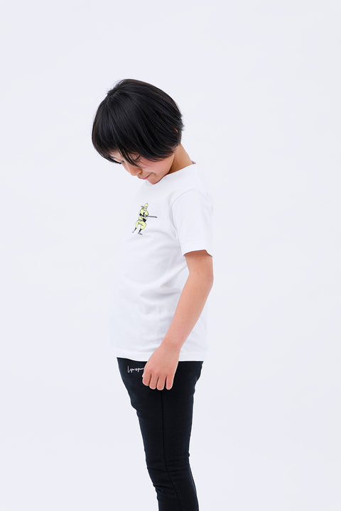 Side view of the child in the "Ninja" T-shirt and pants, looking down slightly.