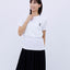 Front view of a smiling woman wearing the white "Five-story Pagoda & Kaiju Monster" T-shirt and a long black skirt, posing with one hand near her chin.