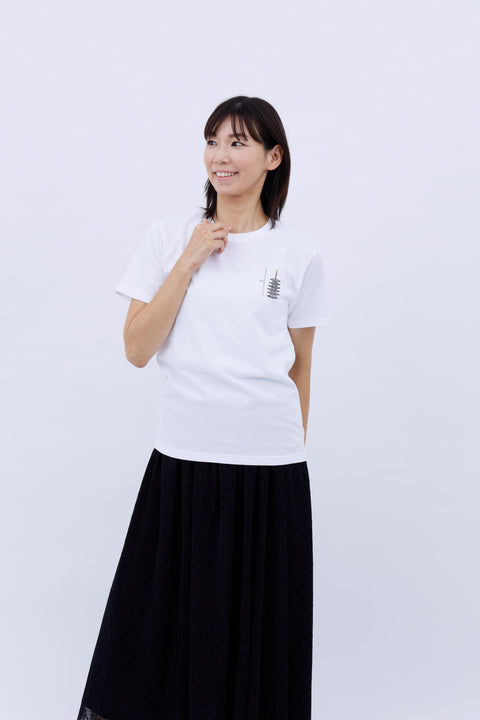 Front view of a smiling woman wearing the white "Five-story Pagoda & Kaiju Monster" T-shirt and a long black skirt, posing with one hand near her chin.