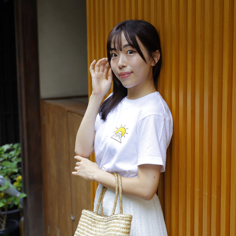 A woman wearing a T-shirt with a “Mt. Fuji First, Hawk Second, Eggplant Third” design.